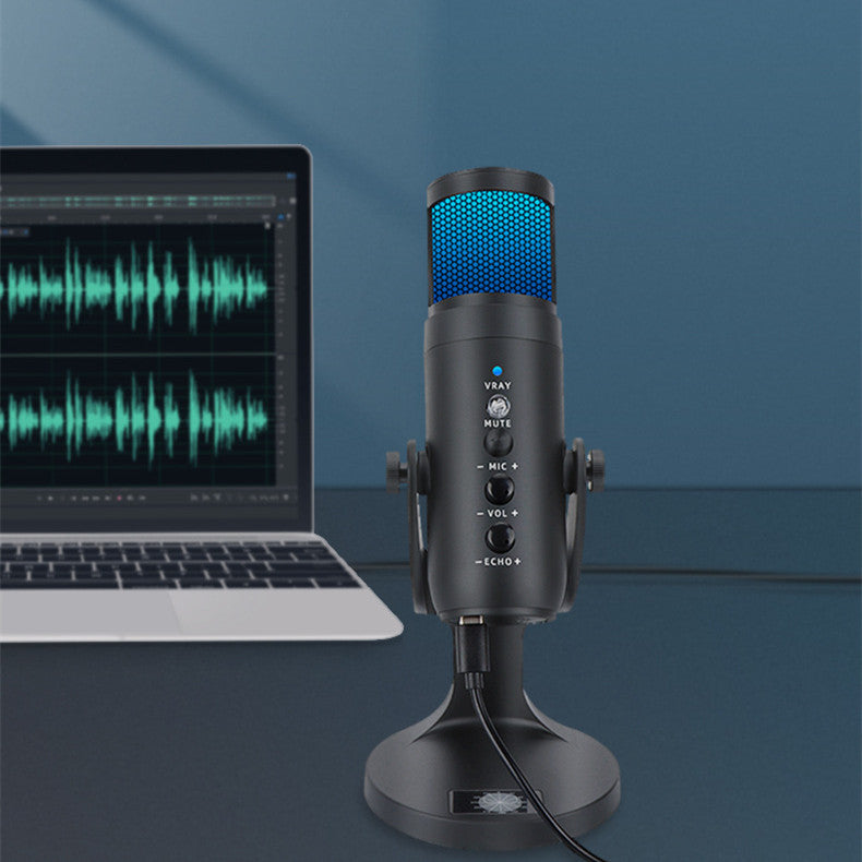 RGB USB condenser microphone on desktop stand next to laptop